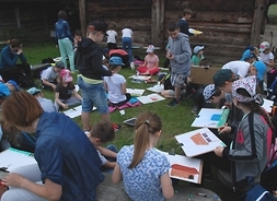 Młodzi uczestnicy konkursu wykonują prace plastyczne na terenie skansenowskiej wsi