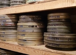 Półka z metalowymi pudełkami zawierającymi taśmy filmowe