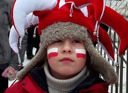 Młody kibic sportowy w biało-czerwonej czapce i z flagami na policzkach