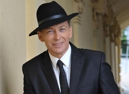 Aktor w garniturze i eleganckim kapeluszu