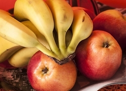 Zdjęcie przedstawiające talerz z kiścią bananów i kilkoma jabłkami