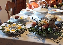 Stół wielkanocny z widocznymi pisankami, gotowanymi jajkami, żurkiem, pieczonym drobiem i prosiakiem