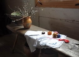 Drewniana ławka pod oknem z wazonem z baziami i rozpoczętą robótką ręczną