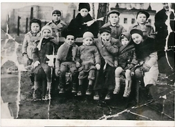 Grupa 11 dzieci w zimowych ubraniach siedzących na drewnianej ławce. Jedno z dzieci gra na harmonijce ustnej