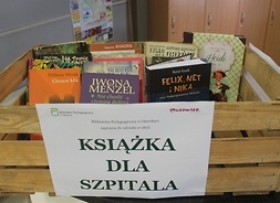 Drewniana skrzynka pełna różnych książek, z kartką na boku z nazwą akcji „Książka dla szpitala”