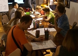 Na zdjęciu uwidoczniony jest stół przy którym siedzą uczestnicy warsztatów organizoanych w ramach imprezy