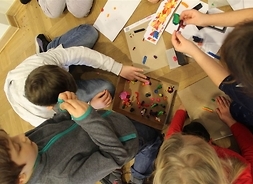 Grupa dzieci podczas zajęć plastycznych bawi się plasteliną. Zdjęcie wykonane z góry