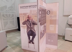Fragment wystawy, przedstawiający ustawione pionowo plansze ze zdjęciami i informacjami dotyczącymi profesora Bartoszewskiego.